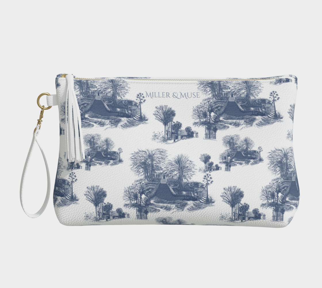 A pebble textured cosmetic case with a hand-drawn blue and white toile de jouy style print featuring the architecture of Beaufort South Carolina such as the Robert Smalls House, Hunting Island Lighthouse, shops on Bay street and the Succession House Steps. The cosmetic case has a wristlet strap and a gold metal zipper.