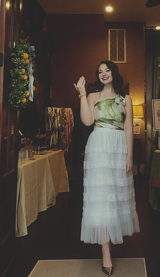 Woman standing in the doorway of a small event venue. She is wearing a white tulle skirt, and green and white silk scarf inspired by the neighborhood of Habersham in Beaufort,SC.